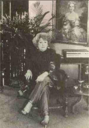 Christine Jorgensen in her home in 1984, sitting below a portrait of herself